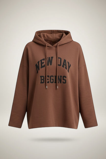 Restless brown oversized hoodie with black "New Day Begins" graphic print on the chest. Long sleeves, drawstring hood.